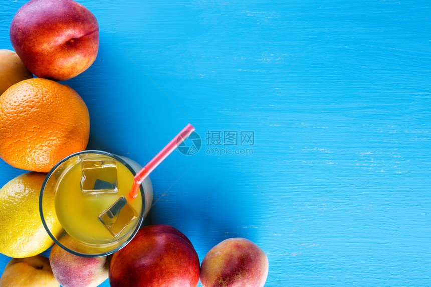 自然成熟橙新鲜的热带水果和一杯蓝色背景加冰的果汁从上方查看食物背景健康天然食品的概念新鲜热带水果和一杯加冰的汁图片