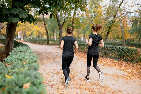 年轻的合身有一对女人跑在公园外的路上快乐图片