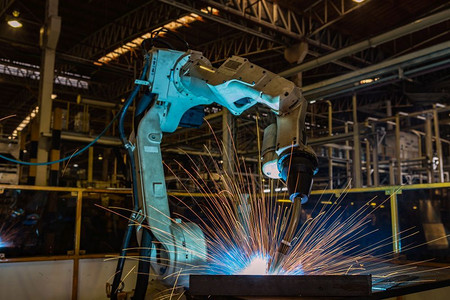 焊机械的现代团队工业机器人在厂中焊接金属部分图片