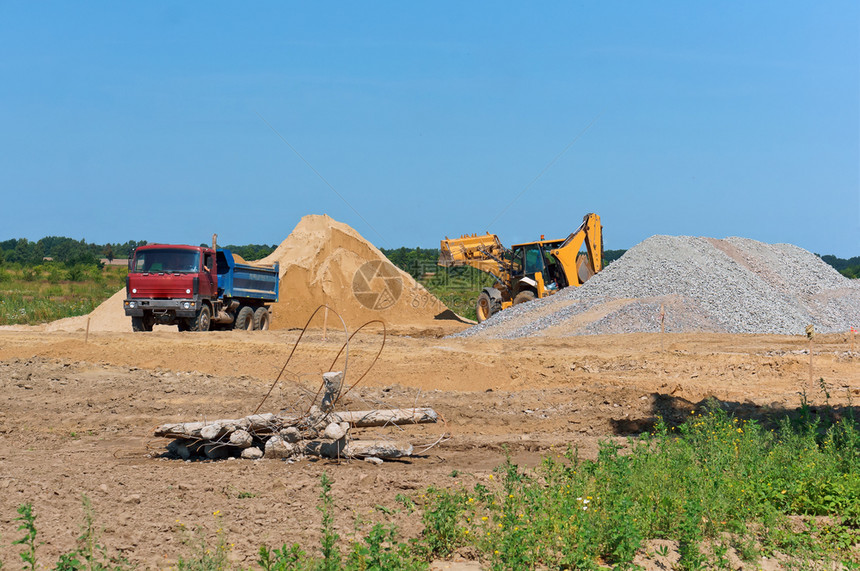 下一个堆沙子旁边的卡车和挖掘机采石场砂一堆沙子旁边的卡车和挖掘机装载桩图片