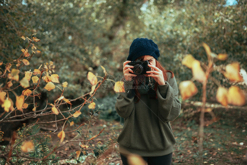 徒步旅行者年轻女子用旧的模拟相机在森林里拍照年轻的豆图片