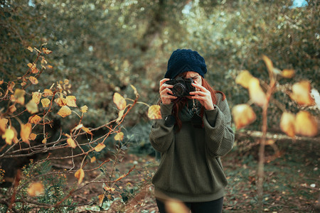 徒步旅行者年轻女子用旧的模拟相机在森林里拍照年轻的豆摄影师高清图片素材