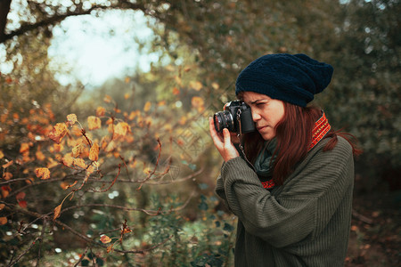 户外年轻女子用旧的模拟相机在森林里拍照远足人们年轻的高清图片素材