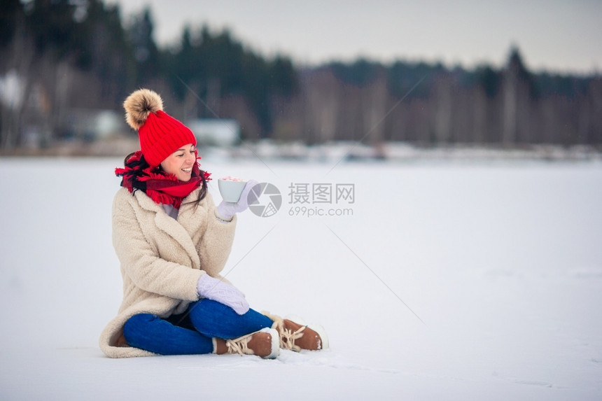 保持墨水女手指戴红帽子和围巾的快乐女孩穿着红帽子和围巾的欢快女孩喝着热咖啡棉花糖在白色杯子中的棉花糖在户外手握着图片