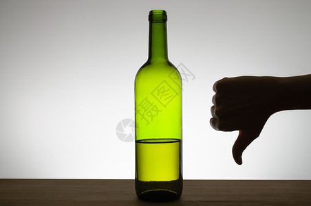 虐待液体在一瓶酒旁边的手表下显示拇指的手影势高清图片
