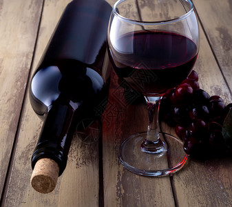饮料瓶子美食酒红杯和葡萄瓶在旧木制桌上装满玻璃和葡萄的酒瓶图片