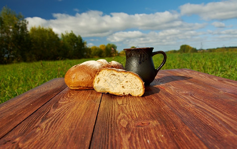 木桌上的自制面包和杯奶地下蓝天空户外农场式部所有的表背景图片
