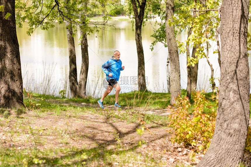 公园健康oopicapi一名身穿黑色和蓝衣服的老人在温暖春日里正在靠近湖边图片