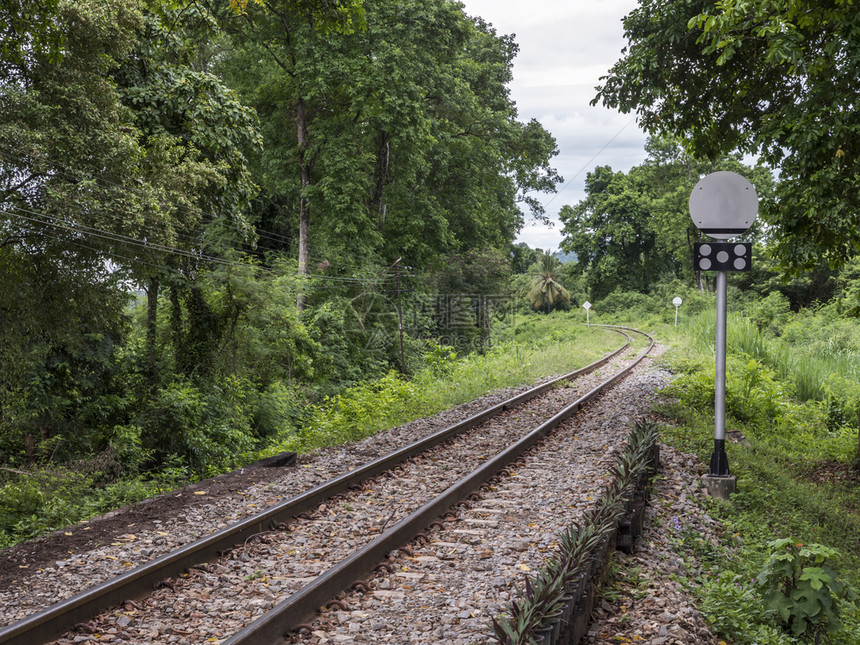旅行山金属在泰国热带森林与交通信号杆汇的铁路线弯曲在泰国热带森林中图片