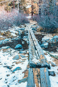 山间溪流森林中的小径雪下木板桥结石乡村的木头背景图片
