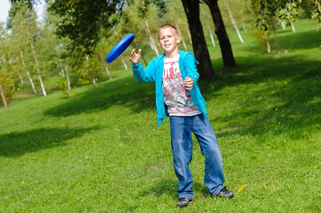 愉快娱乐积极的小男孩在青草上玩飞盘图片