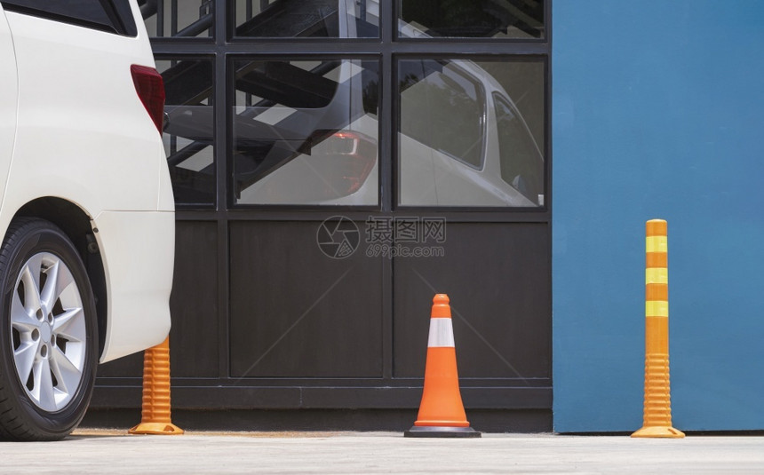 白色的安全警告在现代餐馆玻璃墙边停车场一行的橙色交通锥形和塑料杆白色停车场以及现代餐厅玻璃墙旁的白色停车场图片