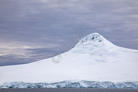 水分层的南极洲海面覆盖着冰雪的山峰面对云雾的天空连接图片