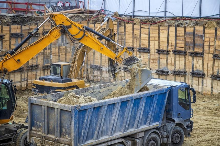 搬运工地球挖掘机正在卡车上装载挖掘作业建筑工地的重型设备在施工中进行作机械图片