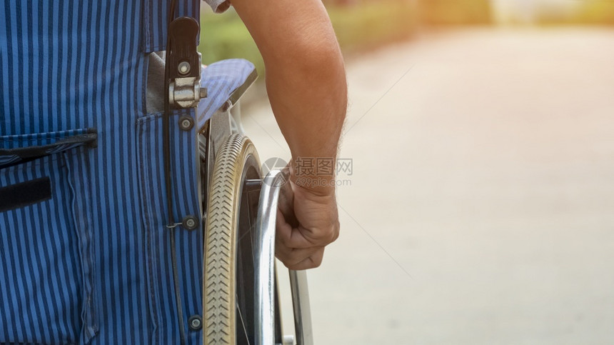 保持禁用残疾人手将轮椅推到公共园路面上与复制空间密闭的残疾人近视卫生保健图片
