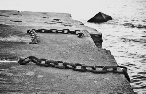 黑色和白混凝土码头的船锚用旧生锈铁链贴近画面条有质感的环境背景图片