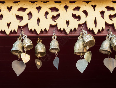 宗教的戒指装饰泰国教堂区木屋的棚上不需要财产放行的心形尾巴小黄铜铃用于装饰泰国教堂区的木叶子文化背景图片