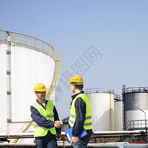 石化握手粗野两名石油工业人在化炼厂储罐前握着手图片