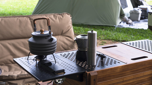 露营桌上的黑水壶和咖啡研磨机背景图片