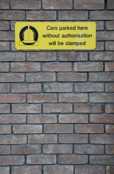 非法的未经批准停泊在这里的黄色汽车将被封在灰砖墙背景上的标记infowhatsthis正面黄色的图片