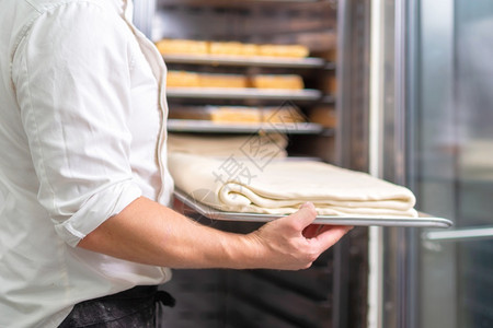 糕点厨师把面粉的托盘放进冰箱糕点厨师把面纸的托盘放进冰箱手工人推杆图片