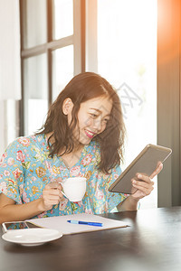 亚洲人以电脑平板牙齿状笑脸和右手咖啡杯为主的计算机片块读信息写幸福图片
