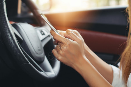 里面亚裔妇女在路上驾驶汽车使用智能手机在路上女事故危险的高清图片素材