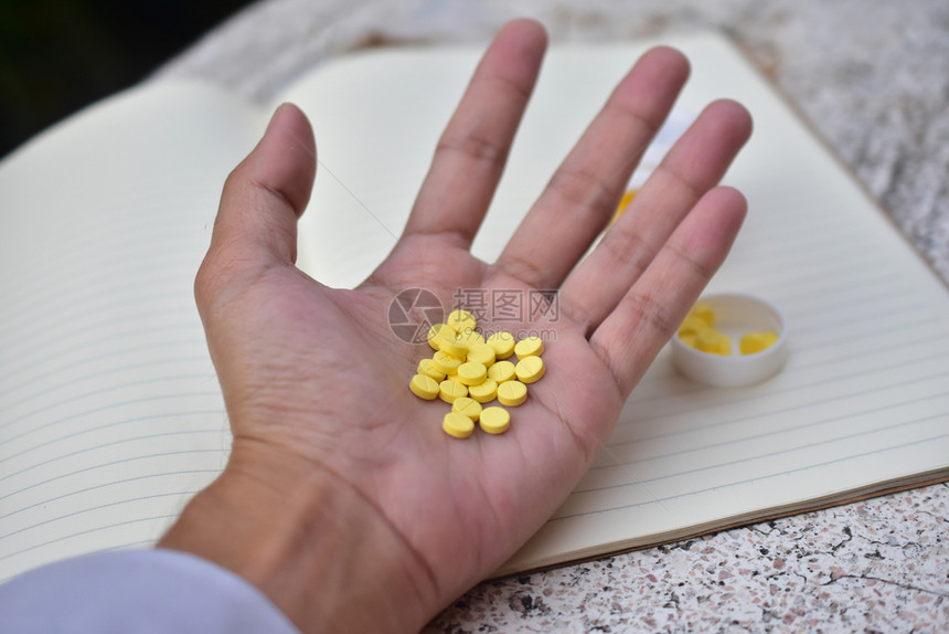 手里的黄色药品药片图片