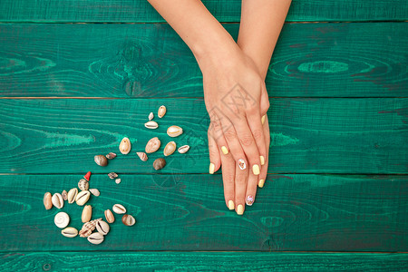 时髦的女手掌与美丽的指甲夏季模式和在绿色背景上从到下看的风景手指艺术图片