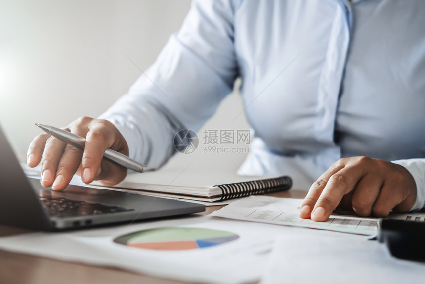 在办公室工作的会计在案头财务和会计概念方面使用电脑笔记本税数据手图片
