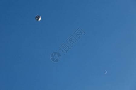 夏天飞行和月亮中的黑白气球从下方观测到蓝色天空中和月光观察到黑色和白气球骑颜背景图片