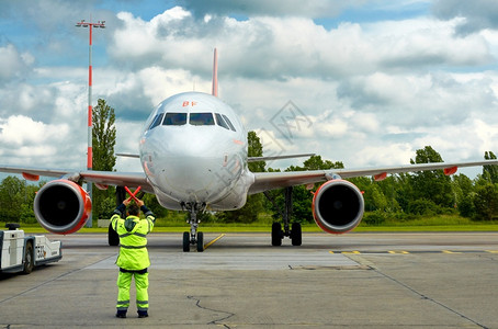 引擎宽的身体男子在停机坪上用红色棍子给飞机标志运输图片