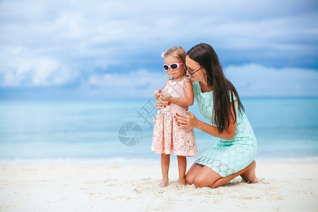 妈和她女儿在海滩上可爱的小女孩和年轻母亲在热带白沙滩上她妈和女儿在海滩上绿松石年轻的幸福女士高清图片素材