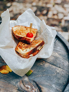 棕色的在木制户外餐桌上的三明治纸配着火腿和奶酪的烤面包意大利粉加火腿和奶酪快速地可口图片