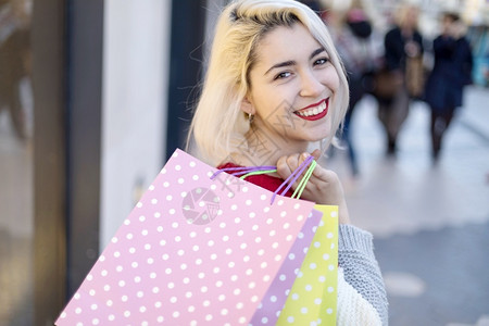 一位带着购物袋的快乐笑容年轻女子肖像携带购物狂愉快图片