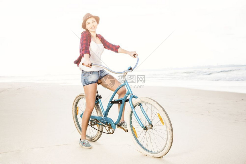 旅行健康一个有魅力的年轻女子在海滩上骑着自行车积极的图片