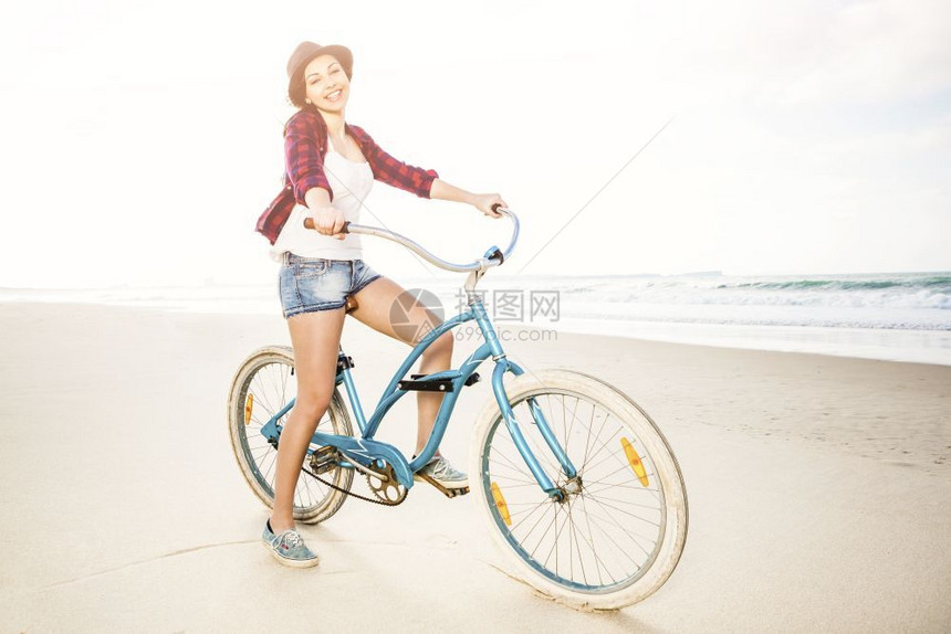 健康一个有魅力的年轻女子在海滩上骑着自行车由海洋图片