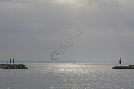 蓝色的港口岩石1月西班牙马洛卡Mallorca以帆船和阳光在两座码头之间开通时用帆船和阳光观视海洋背景
