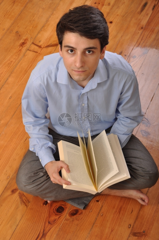 男木制的在家坐地板上看商业书的有吸引力年轻男青在阅读商业书籍现代的图片