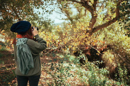 自然年轻女子用旧的模拟相机在森林里拍照植物女漂亮的高清图片素材