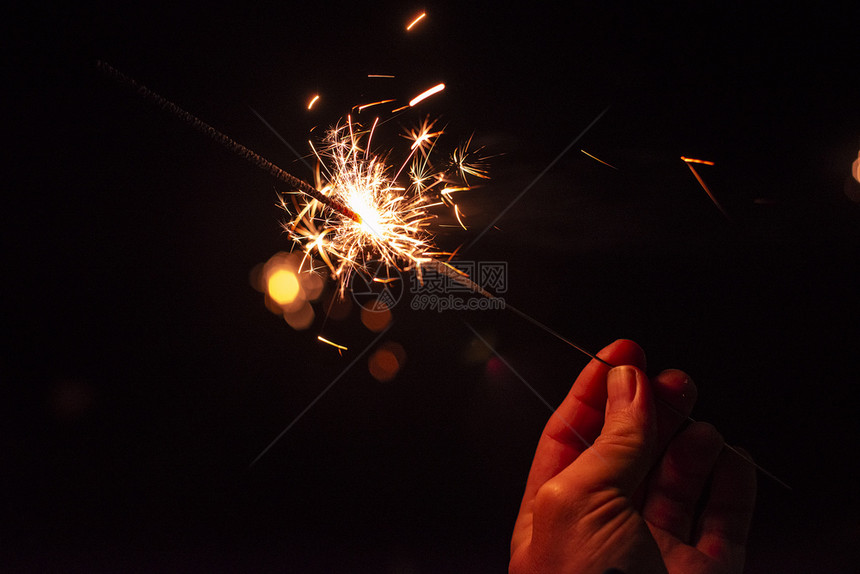火焰新年的派对花雄用手紧贴着未散暗底幕下的男人拿着闪亮的节日火花抽象手持式图片