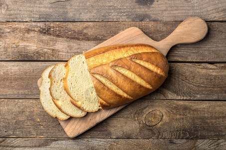 自制美味的有机厨房板和木制餐桌上的长面包切成肉片从上面包到木制桌图片