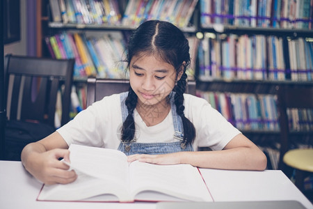 亚洲女孩在图书馆书架前阅读图片