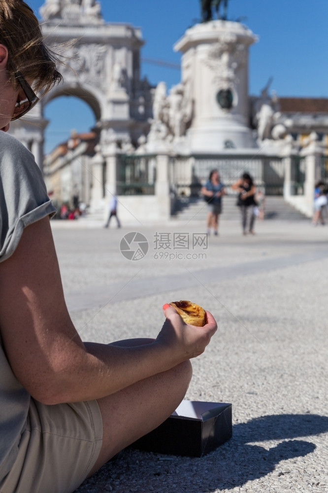 黄色的在葡萄牙里斯本的背景点上葡萄牙传统妇女手中的Pasteisdenataspathesnata糕点午餐图片