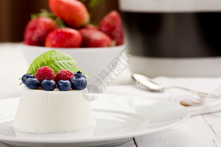 白木桌边有浆果的美味pannaCotta照片热量盘子食物图片