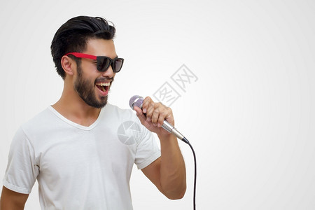 成人保持带着胡子的亚洲英俊男笑着歌唱在白色背景上被孤立的麦克风声音图片