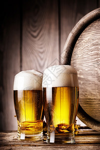 两杯轻啤酒放在木制桶底的两杯轻啤酒上茶点葡萄缩合图片