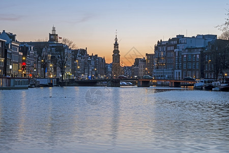 美丽的来自荷兰阿姆斯特丹的城市景点日落时有月塔旅行河背景图片