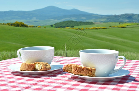 与意大利托斯卡纳风景对比的彩布上两杯咖啡和罐头早餐曲奇饼锡耶纳图片