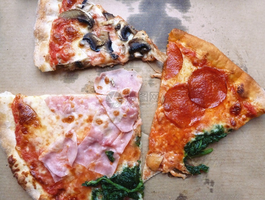 披萨剩菜的顶端景色在外卖的纸板盒里切碎配有象棋火腿沙拉米菠菜和真菌的奎特罗斯塔吉尼比萨一顿饭最佳照片图片
